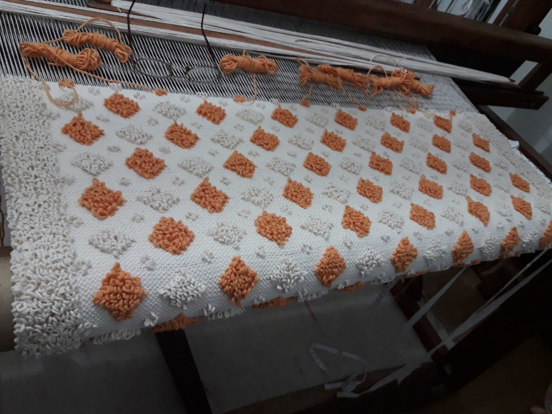 1º Pibione Adaptado pelo Isatramas Curso PIBIONES: Uma Técnica Sardenha. Foto de peça ainda presa em tear de pedal. Esta peça é um tapete e foi tecido na técnica pibiones.