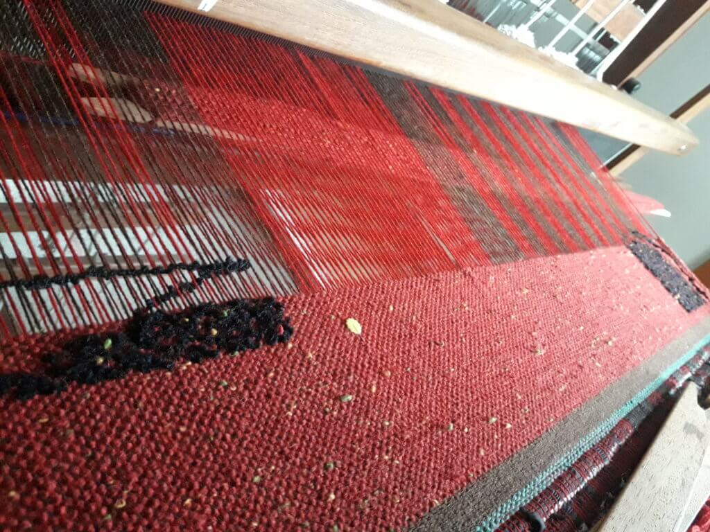 Comecei a Tecer: Como a Tecelagem Mudou Minha Vida — e Pode Mudar a Sua Foto de tecido sendo feito em tear de pedal com alternância de ponto tela e padrão em gráfico. Esta imagem ilustra post: 5 Motivos para Você Produzir Presentes neste Natal