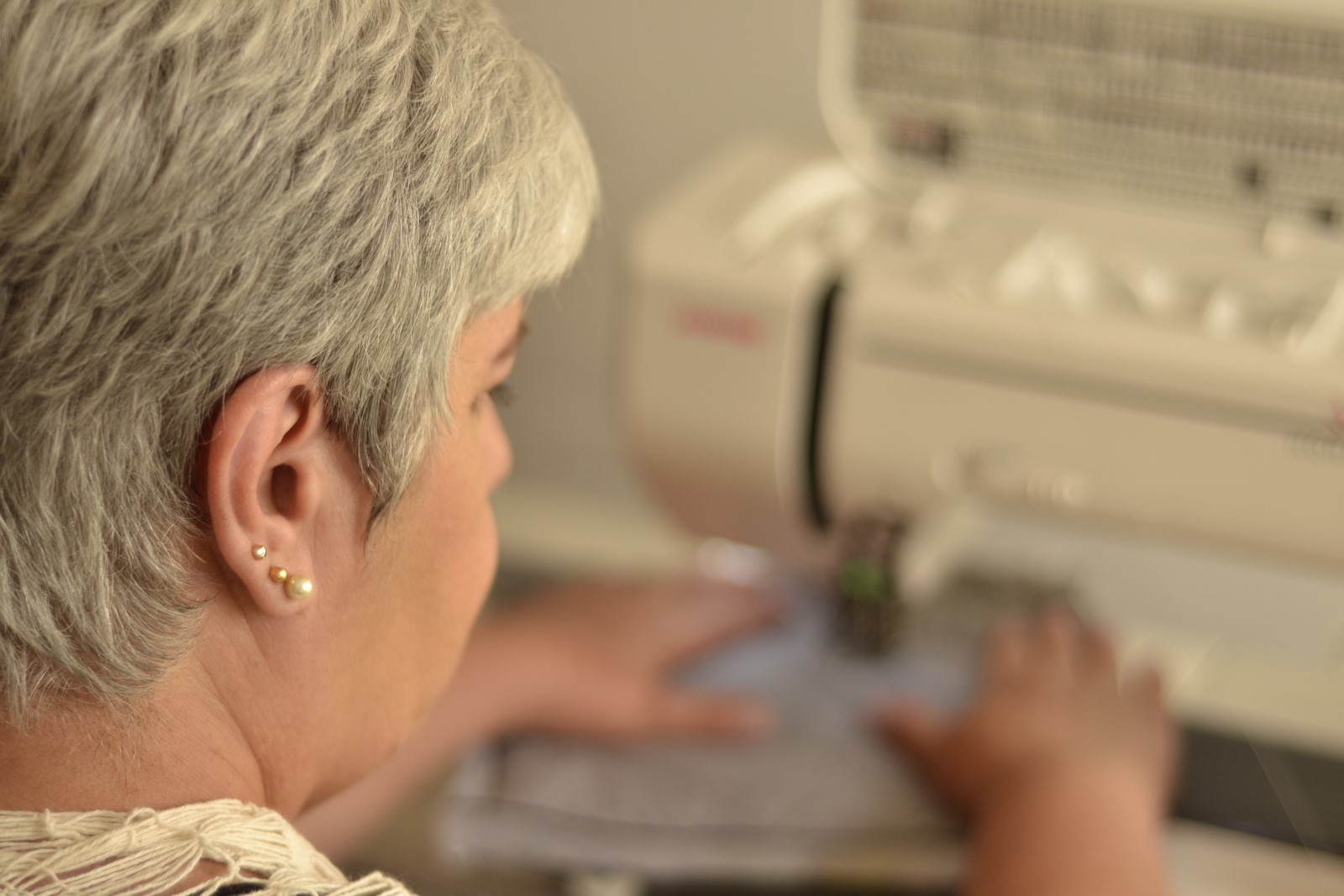 Quebre o bloqueio de tecelão. Foto de Isaura Mattos na máquina de costura doméstica, quiltando uma amostra.